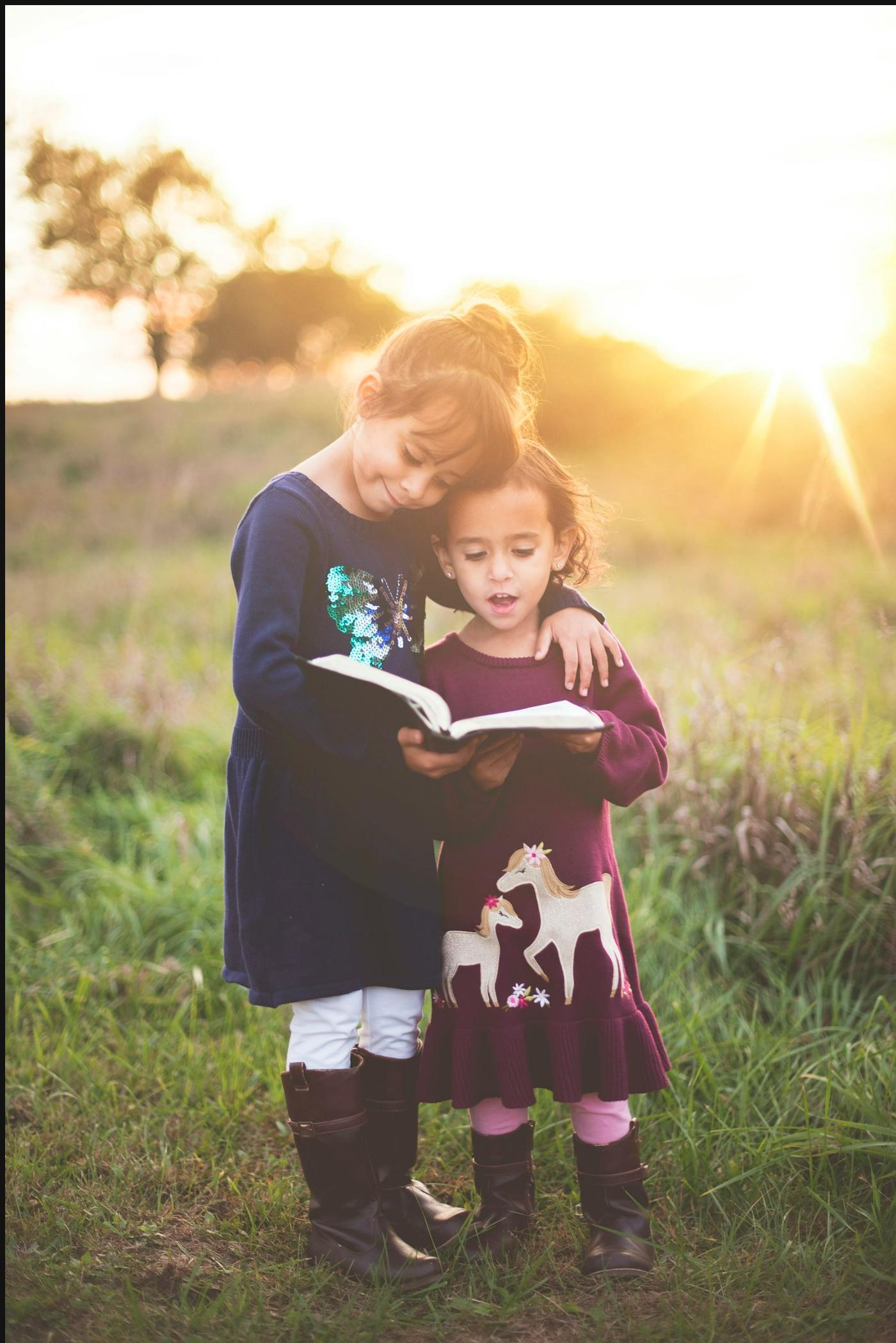 Two children reading a book together in warm evening light